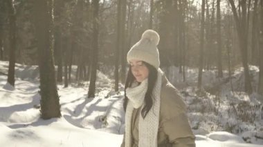 Güzel ve genç bir kız kışın ormanda yürür ve gülümser.