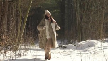 Ağır çekim. Karlı orman. Güzel kız kameraya gidiyor..