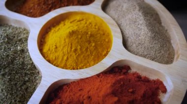 Baharat görüntüsü. Ahşap masa üzerinde çeşitli Hint baharatları. Zerdeçal, kırmızı biber, kırmızı biber, kırmızı biber, kırmızı biber ve kekik üzerinde döndürülmüş.