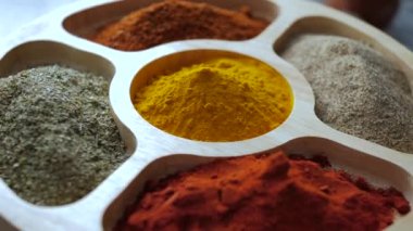 Baharat görüntüsü. Ahşap masa üzerinde çeşitli Hint baharatları. Zerdeçal, kırmızı biber, kırmızı biber, kırmızı biber, kırmızı biber ve kekik üzerinde döndürülmüş.