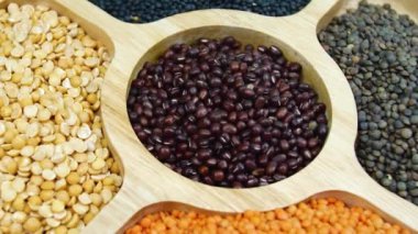 Tahta masada baklagillerin karışımı. Döndürme sütunları kapatın. Tahta masadaki baklagiller. Sağlıklı beslenme, vejetaryen yemek görüntüleri. Legumes Lezzetli ve Sağlıklı Doğal Karışık Yiyecekler 