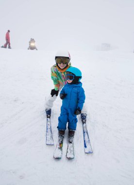 Küçük çocuk ve genç kız dağlarda kayak yapıyor. Aile için kış sporları. Kayak okulunda kayak dersleri. Çocuklar için kışın aktif eğlence, spor eğitimi. Etkin çocukluk