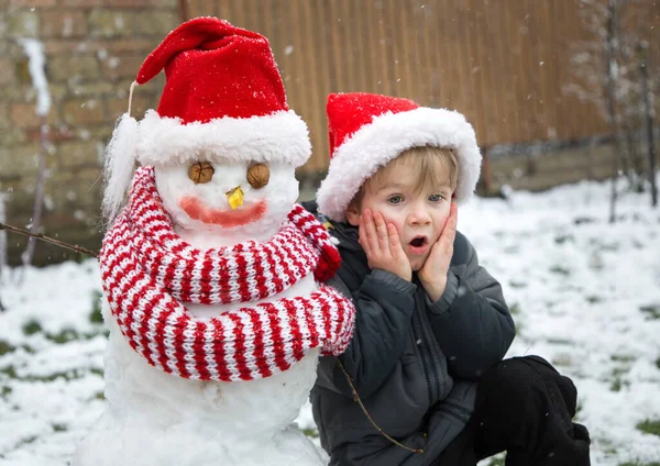 Emotional Surprised Alarmed Boy Sits Snowman Both Wearing Santa Hats — Stock Photo, Image