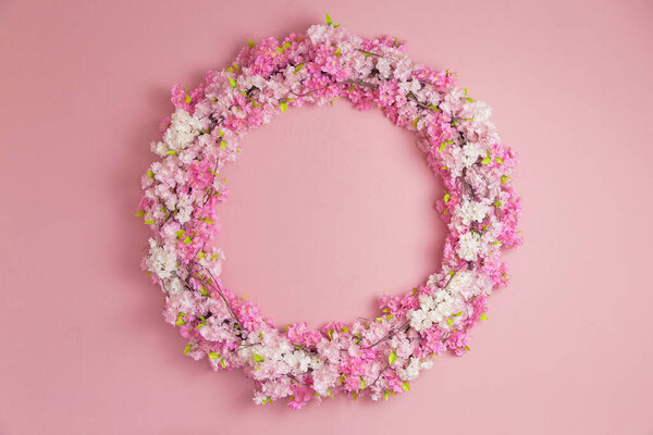 beautiful round frame woven from blooming spring twigs on a pink wall, Spring mood in the interior, hello spring, cozy atmosphere, spring is in the air