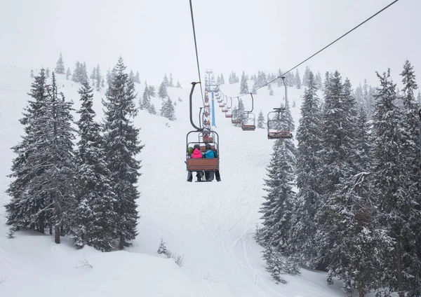 Remonte Que Lleva Esquiadores Irreconocibles Sobre Abetos Cubiertos Nieve Ladera — Foto de Stock