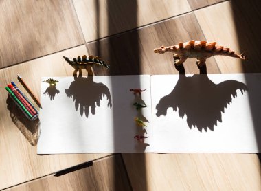 Işık ve gölgeyle oynamak. Oyuncak dinozor figürünün gölgesini çiz. Çocukluk, evde çocukların yaratıcılığının gelişmesi için oyunlar