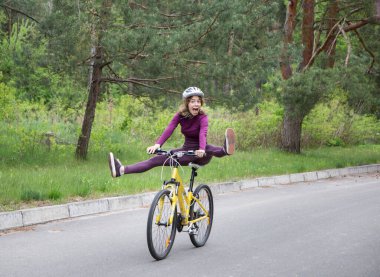Hareket halindeki bisikletli kasklı duygusal bir kızın komik portresi. Ayaklarını pedallardan çekerek bisiklet sürerken eğleniyor. sağlıklı aktif yaşam tarzı. Açık hava bisikleti