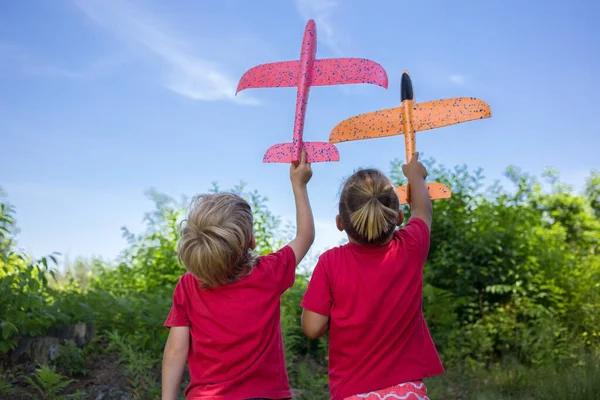 赤いTシャツを着た2人の男の子が背を向けて立ち 空を背景に大きなおもちゃの飛行機を手にしている ゲーム 飛行機のパイロットになるために 旅に飛ぶ欲求の概念 — ストック写真