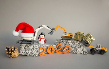Oyuncak kazıcı modelleri, granit parçaları üzerine yükleyici, hatıra olarak bir kardan adam, bir Noel Baba şapkası. Yeni yıl iş tebrikleri, inşaat şirketlerinde yeni yıl tatili