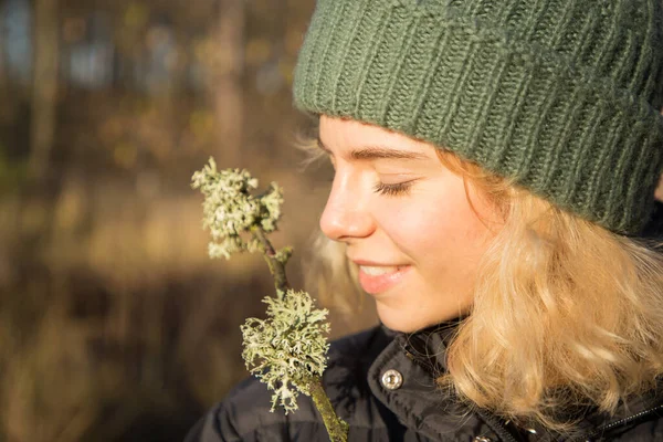 profile portrait of a beautiful smiling teenager girl of 17 years old in a knitted green hat. Sunny day, walking in the forest, enjoying the moment, digital detox