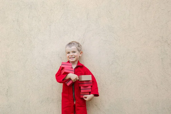 Sonriente Niño Lindo Uniforme Mono Rojo Sostiene Muchas Cajas Pequeñas — Foto de Stock