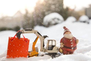 İki oyuncak kazıcı modeli, bir hediyelik Noel Baba, karda bir hediye çantası standı. Noel iş tebrikleri, inşaat şirketlerinde yeni yıl tatili konsepti. Güneşli kış tatili