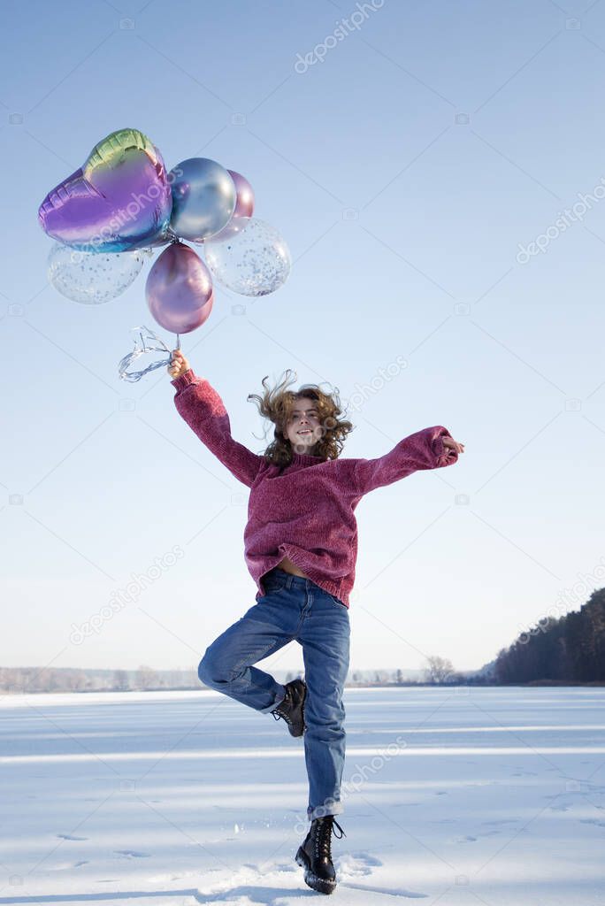 graceful slender cute teenage girl, holding many colorful balloons in her hands, jumping up on the snowy ground. winter holidays. Joyful emotions, vitality, no problems. fun, surprise, joy