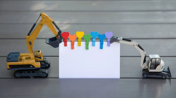 models of toy excavators hold blank sheet of paper for text. place for announcement, advertising, business - congratulations to construction company, technical service, construction equipment leasing