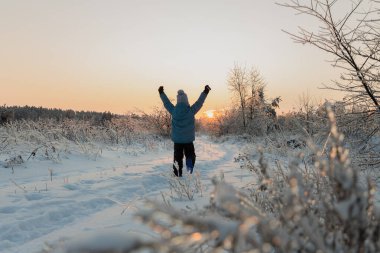 Tanınmayan bir çocuk kış manzarasının arka planında güneşe doğru koşar. Açık, güneşli, soğuk, açık havada, buzla kaplı. Daha parlak bir geleceğe. Arka plan.