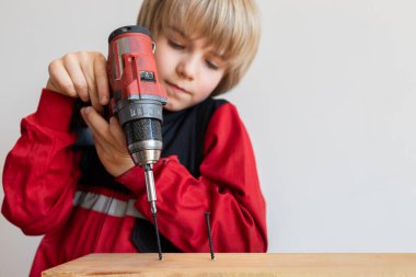 Çocuk aletlerle çalışmayı öğreniyor. İş sırasında elinde tornavida olan bir çocuğun yakın çekimi. Oyun yoluyla öğrenmek, tecrübeyi genç kuşağa aktarmak..