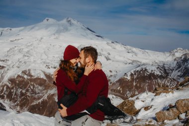 Karlı bir dağın zirvesinde duran genç bir çiftin görüntüsü