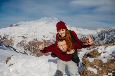 Karlı bir dağın zirvesinde duran genç bir çiftin görüntüsü