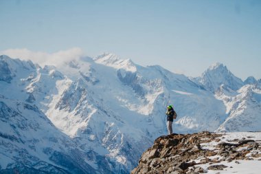 Karlı bir dağın zirvesinde duran genç adama bakın.