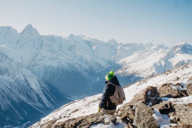 Karlı bir dağın zirvesinde duran genç adama bakın.