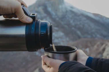 Termos ve çay tutan ellerin yakın görüntüsü 