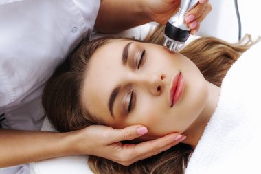 Radyoaktif yüz gerdirme ameliyatı olan kadın. Donanım yüz kozmetolojisi. RF fotoğrafı kaldırıyor.