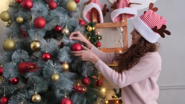 모자를 아름다운 여인이 집에서 크리스마스 트리를 장식하고 — 비디오