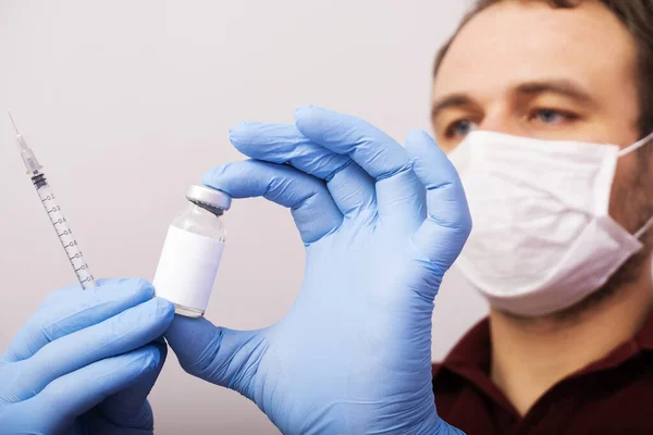 doctor in a mask holding a syringe and vaccine  in the laboratory