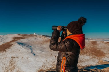 Uzağa bakan dürbünlü genç bir kadın.