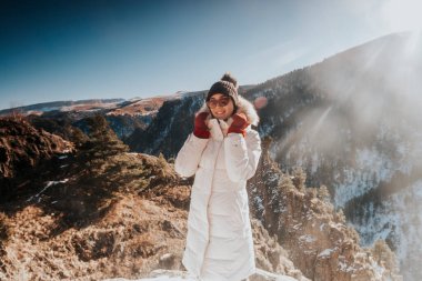 Kışın giyinmiş güzel bir kadın dağlarda poz veriyor.