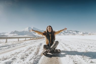 Genç bayan dağlarda karların üzerinde oturuyor.