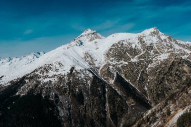 Güneşli havada dağların karlı tepeleri. Dombai dağları kapanır.