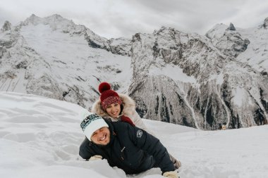 Kışın karda sevgi dolu bir çift. Adamın şapkasında Rusça Elbrus harfleriyle yazılmış bir yazı var..