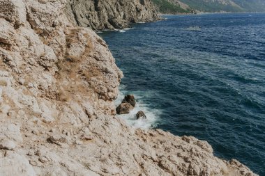 Dalgalar kayalara çarpar. Mavi göl ve kayalar.