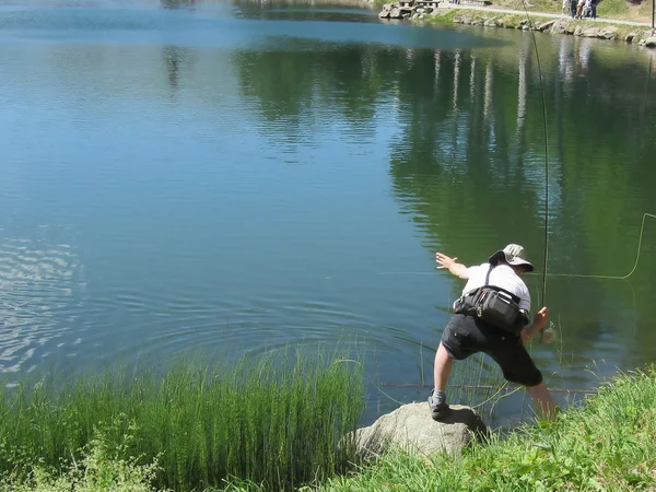 Homem pesca com mosca em um lago de montanha — Fotografia de Stock