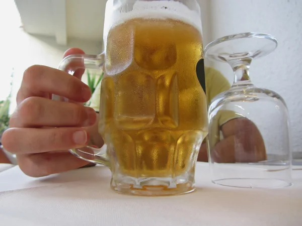 Mannelijke hand met een koude mok licht bier — Stockfoto