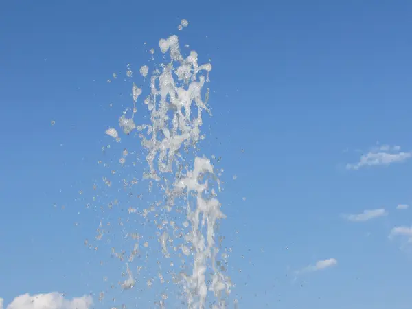 Eau pulvérisée d'une fontaine contre le ciel bleu — Photo