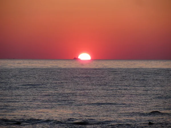 İçinde belgili tanımlık geçmiş kargo gemisi ile sıcak deniz günbatımı — Stok fotoğraf