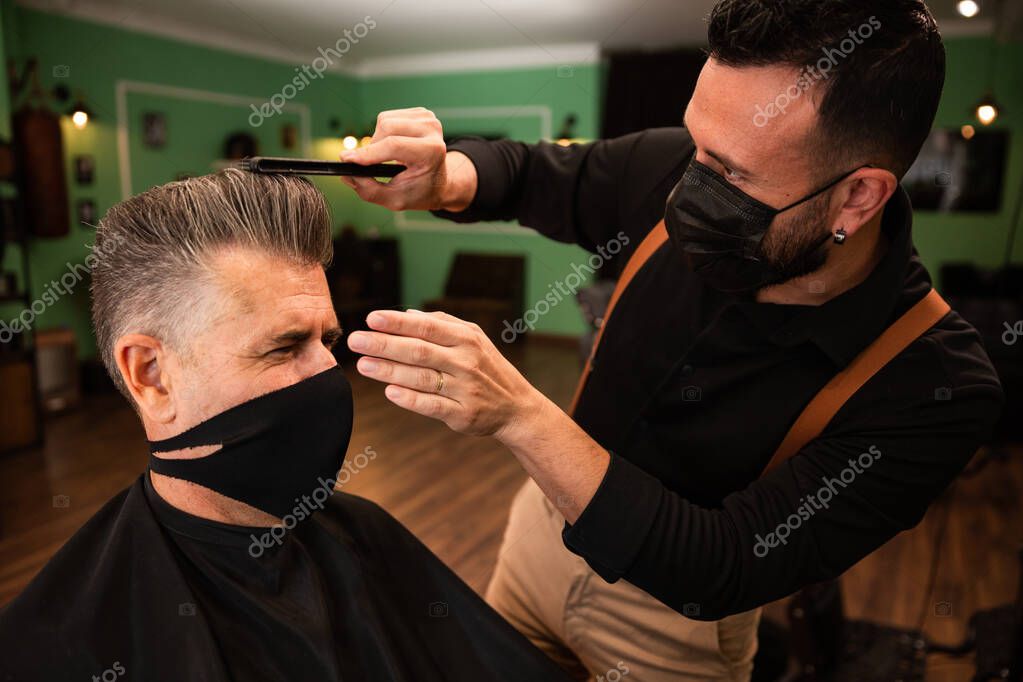 en una peluquería un peluquero peina a un hombre adulto con su mano y