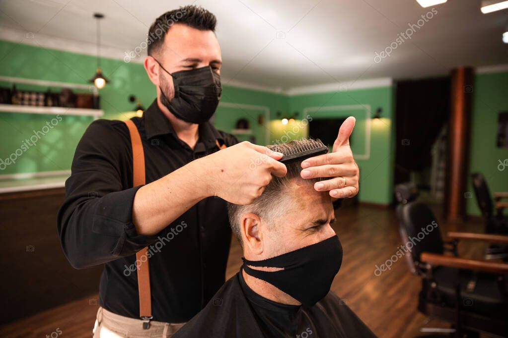 en una peluquería un peluquero peina a un hombre adulto con su mano y