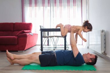 Kafkasyalı baba, Latin annesinin küçük kızıyla spor, spor ve yoga yapıyor. Egzersiz yaparken eğleniyorlar..