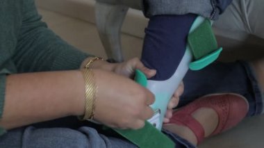 Kafkas kadın yerde oturuyor. Engellilerine ortopedik alçı takıyor. Kanepede oturuyor, protez.