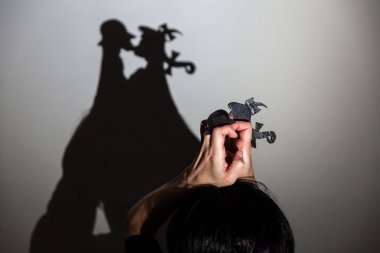 play shadow projected on a white screen. the person's hands shape two little people talking and kissing clipart