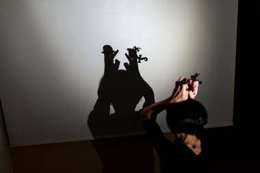 Beyaz ekrana yansıtılan gölgeyi oynat. Elleri konuşan ve öpüşen iki küçük insanı şekillendirir.