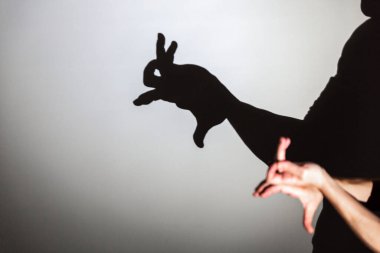 play shadow projected on a white screen. the person's hands shape a rabbit clipart