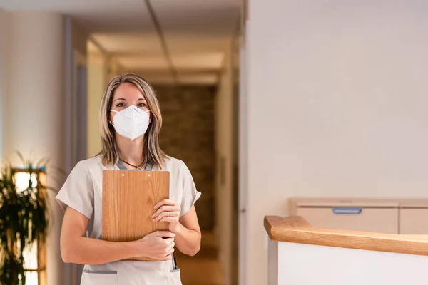 Donna receptionist in possesso di cartella con documenti e con maschera in ospedale — Foto Stock