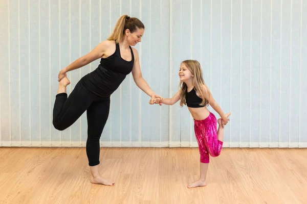 Matka instruktor jogi i córka wykonują ćwiczenia równowagi i rozciąganie — Zdjęcie stockowe