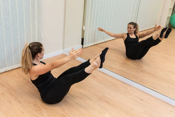 Yoga- und Pilateslehrerin zeigt im Fitnessraum die V-Haltung. — Stockfoto