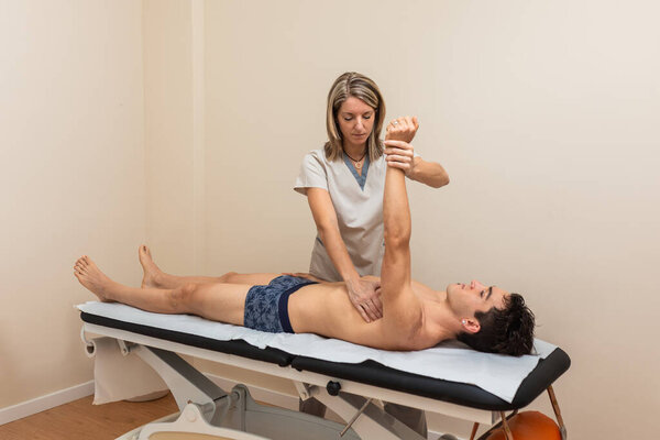 Женщина-физиотерапевт проводит сеанс с мужчиной. тендинит, гленохонеральный