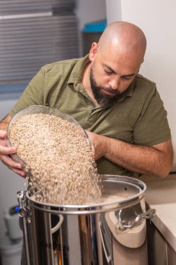 Adam bira yapmak için çaydanlığa arpa ve buğday arpası döker.